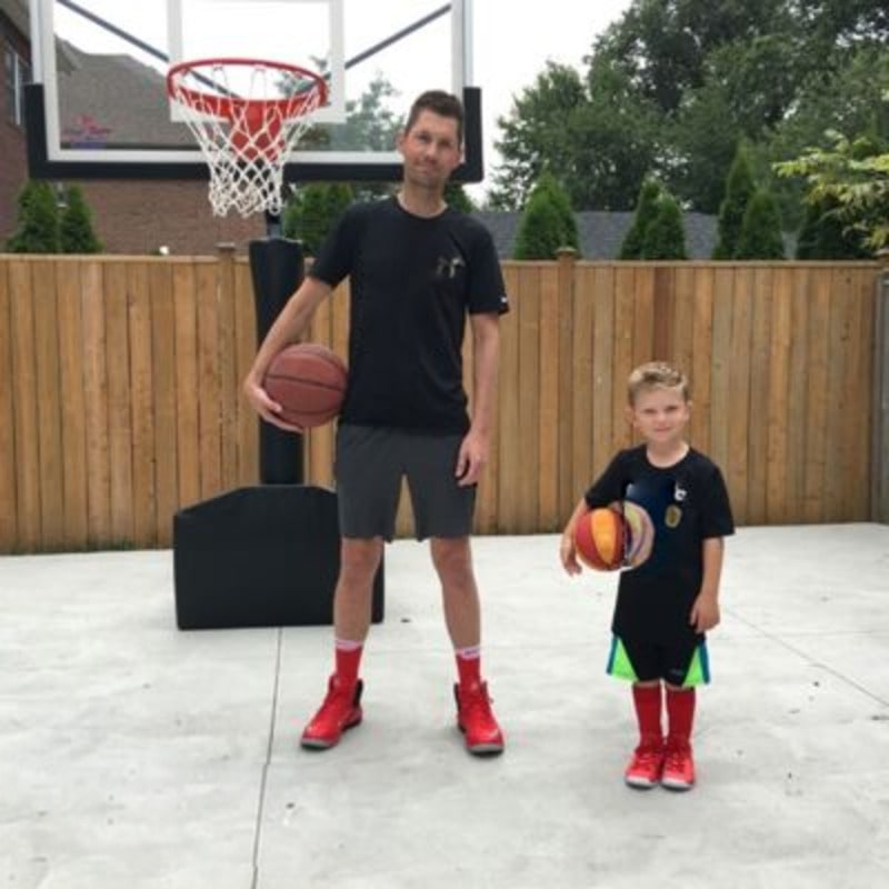 Man and Child outdoor lifestyle image in front of First Team Rampage Portable Basketball Hoop view of Adjustable Height Goal System